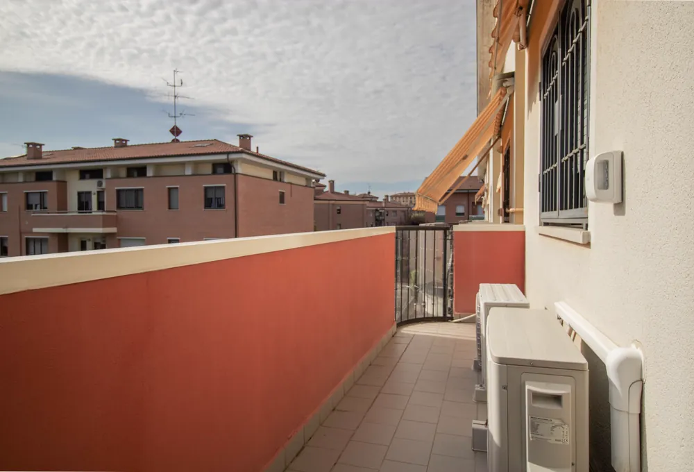 Terrazzo lungo con parapetto arancio e vista sui tetti