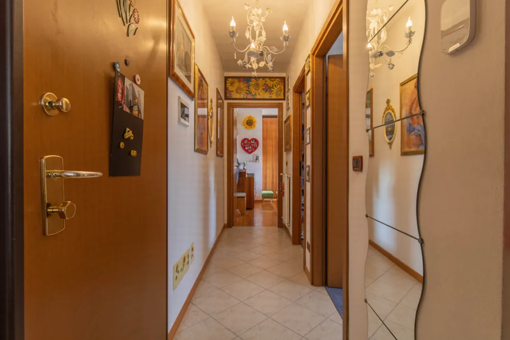 Corridoio d'ingresso con pavimento chiaro e porte in legno